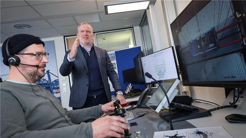 Erste ferngesteuerte Containerbrücken vor Inbetriebnahme HHLA-Firmenchef Eijsink gestikuliert neben einem Mitarbeiter, der eine Containerbrücke steuert.