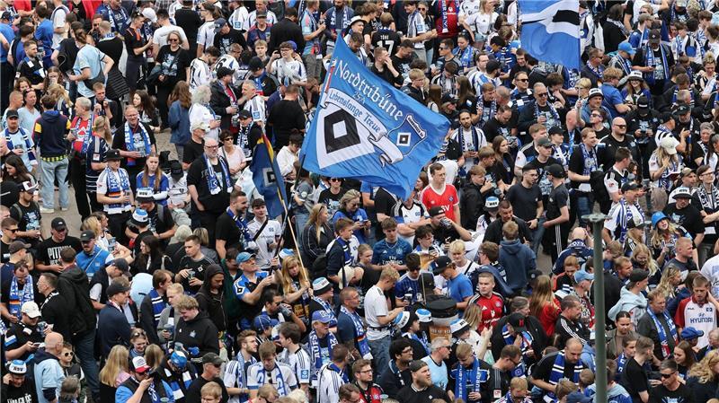 HSV-Fans stehen auf dem Rathausmarkt vor dem Hamburger Rathaus und feiern ihren Club.