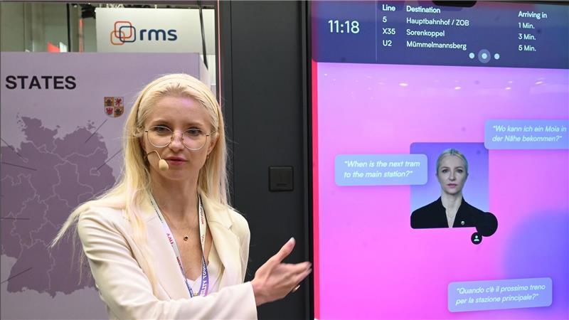 Sprechende Bushaltestelle soll Reisezentren ersetzen HVV-Geschäftsführerin Anna-Theresa Korbutt zeigt auf einen Sprachassistenten mit ihrem eigenen Gesicht.