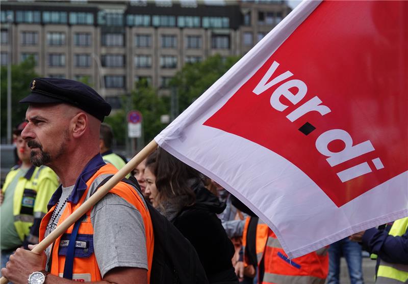 Hafen-Beschäftigte mit Verdi-Fahnen protestieren in der Innenstadt vor der Zentrale der Reederei Hapag-Lloyd. Im Konflikt um die Entlohnung der Hafenarbeiter an den großen deutschen Nordseehäfen ist weiterhin keine Einigung in Sicht. Foto: Julian Weber/dpa