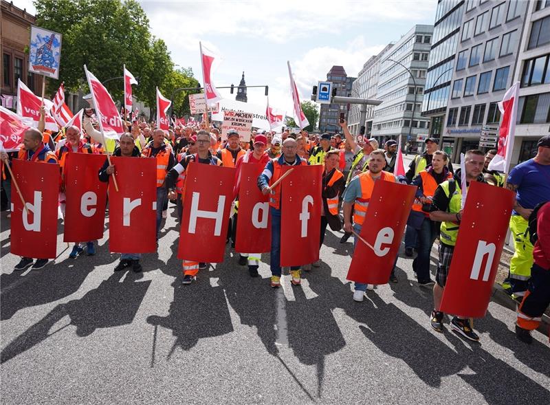 Hafen-Beschäftigte mit Verdi-Flaggen demonstrieren in der Innenstadt. Im Konflikt um die Entlohnung der Hafenarbeiter an den großen deutschen Nordseehäfen ist weiterhin keine Einigung in Sicht. Foto: Marcus Brandt/dpa