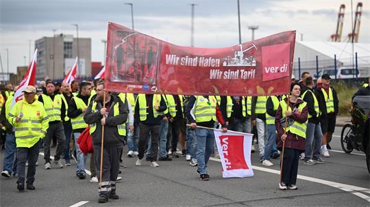 Hafenarbeiter laufen mit einem Banner durch Bremerhaven.