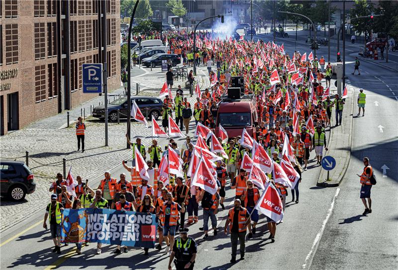 Hafenarbeiter ziehen unter dem Motto „Das Inflationsmonster stoppen“ durch die Hamburger Hafencity. Die Gewerkschaft Verdi ruft Beschäftigte der Seehäfen zum dritten Warnstreik innerhalb weniger Wochen auf. Foto: Axel Heimken/dpa