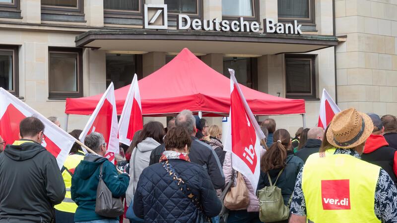 Hamburg: Bei einem Warnstreik stehen Streikende vor einem Gebäude der Deutschen Bank. 