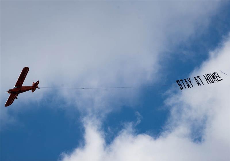 Hamburg: Ein kleines Flugzeug fliegt mit einem Banner mit der Aufschrift "Stay at Home!" (Bleibt zu Hause!) am Himmel über der Innenstadt. Foto: Christian Charisius/dpa 