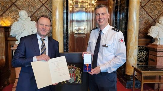 Hamburgs Innen- und Sportsenator Andy Grote (links) überreicht Malte Stüben das Bundesverdienstkreuz. Foto: DRK