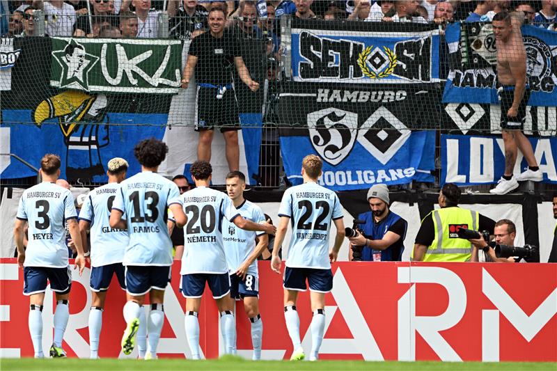 HSV-Fans klagen über Kontrollen vor Pokal-Spiel – Darum ist die Aufklärung schwierig Hamburgs Spieler feiern mit den angereisten Fans das 3:4 gegen Essen. Foto: Federico Gambarini/dpa