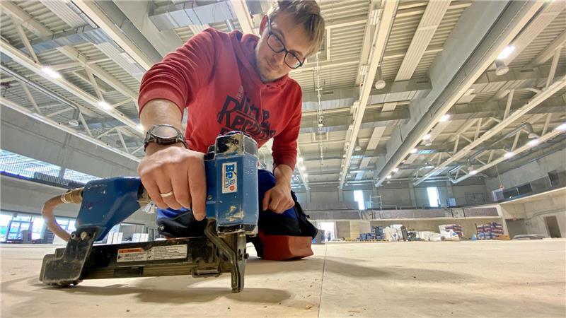 Handwerker verklammern in der Dreifeldhalle derzeit Holzplatten. Später kommt der Hallenboden drauf.