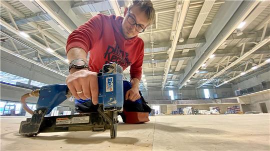 Handwerker verklammern in der Dreifeldhalle derzeit Holzplatten. Später kommt der Hallenboden drauf.