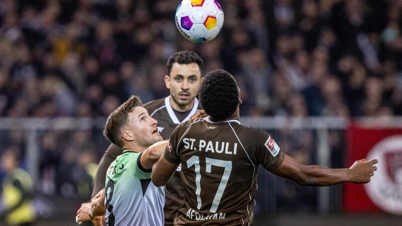 Hannovers Enzo Leopold (l-r), St. Paulis Manolis Saliakas und St. Paulis Oladapo Afolayan kämpfen um den Ball. Foto: Axel Heimken/dpa