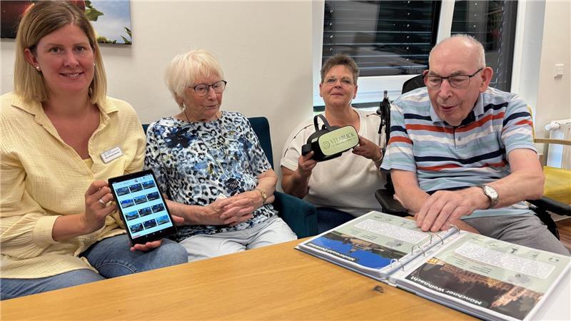 Hans-Uwe Bösch guckt im Katalog, wo die Reise für ihn und Erika Hermann als nächstes hingeht. Einrichtungsleiterin Ann-Christin Martens (links) und Betreuungskraft Ines Bunk halten Tablet und VR-Brille bereit.