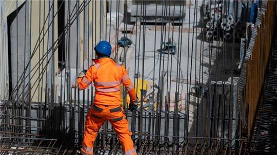 Harter Arbeitsalltag: Ein Bauarbeiter verlegt auf einer Baustelle Stahlmatten.