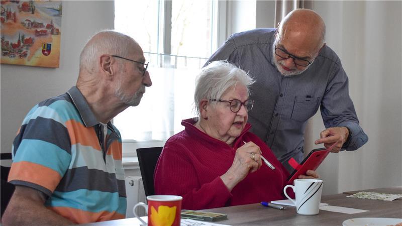 Hartmut Giehler (hinten) und Eckhard Scheinhof helfen Anne Sick, ihr Smartphone richtig zu bedienen.