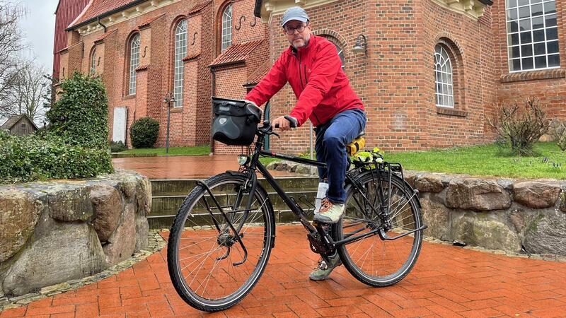 Hasnain Kazim legt vor der Kirche in Steinkirchen eine Pause auf seiner Deutschlandtour ein.