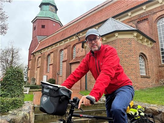 Hasnain Kazim radelt für sein neues Buch durch Deutschland. Er stoppte im Februar vor der St.-Martini-et-Nicolai-Kirche in Steinkirchen. Foto: Vasel