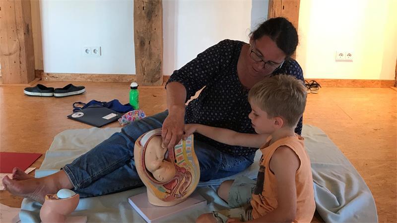 Archäologie, Kunst und die Geburt: Diese Kinder wollen in den Ferien lernen Hebamme Iris Freyer erklärt dem sechsjährigen Felix, dass die meisten Babys mit dem Kopf zuerst geboren werden.