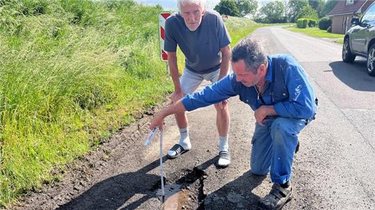 Heinz Meyer und Manfred Höft messen die Tiefe eines Schlaglochs in Bassenfleth.