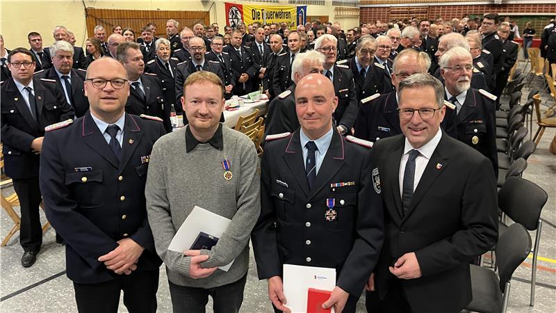 Helfen auch in Lebensgefahr: Kreisbrandmeister Henning Klensang (links) und Landrat Kai Seefried nehmen Stephan Reitz (Zweiter von links) und Ricard Globuschütz in ihre Mitte. 250 Führungskräfte der Feuerwehren erheben sich zu ihren Ehren.