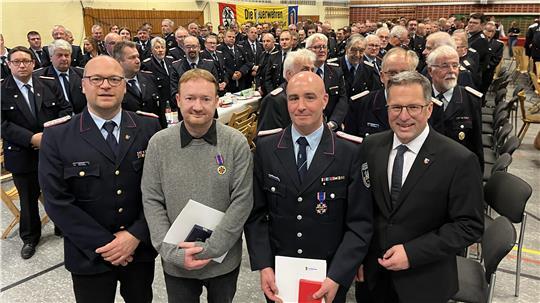 Helfen auch in Lebensgefahr: Kreisbrandmeister Henning Klensang (links) und Landrat Kai Seefried nehmen Stephan Reitz (Zweiter von links) und Ricard Globuschütz in ihre Mitte. 250 Führungskräfte der Feuerwehren erheben sich zu ihren Ehren.