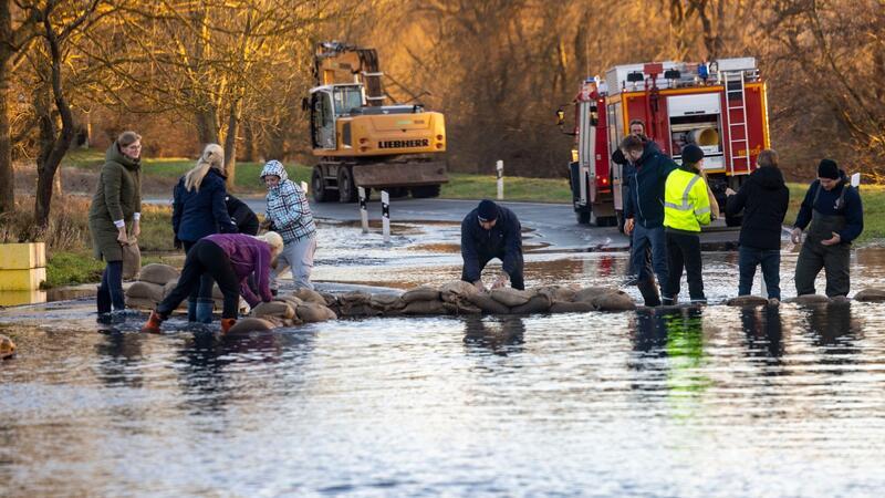 Helfer bauen mit Sandsäcken einen Deich auf einer Straße im thüringischen Windehausen.