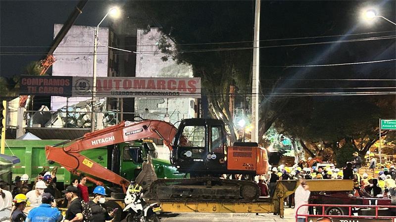 Plötzlich wird es still am Trümmerberg in Cali Helfer bringen einen Bagger zu einem eingestürzten Gebäude.