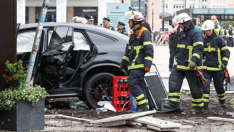 Helfer stehen an einem demolierten Auto vor einer Sparkasse in der Hamburger Innenstadt. 