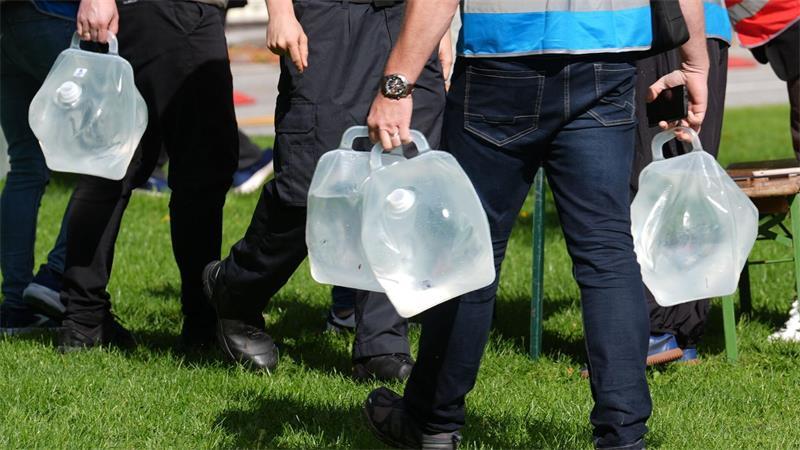 Helferinnen und Helfer tragen Wassercontainer an Tische an der Sammelstelle am Altona Balkon.