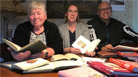Helga Daß, Tochter Antje Funck und Schwiegersohn Jörg Funck (von links) stöbern in alten und neuen Poesiealben und Freundschaftsbüchern.