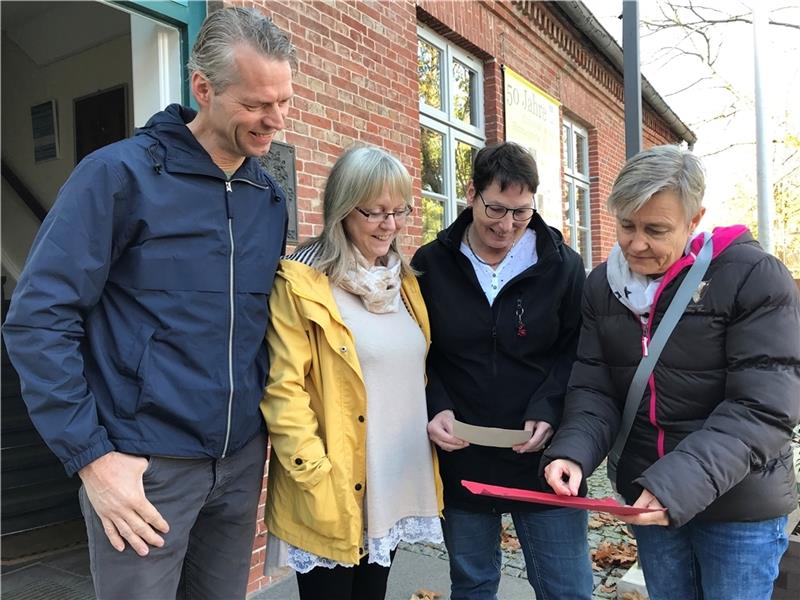 Henrik Burfeindt, Doris Hagenah, Heidi Westphal und Gabriele Lewens (von links) betrachten alte Fotos aus ihrer Kindergartenzeit. Foto: Helfferich