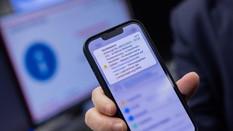 Herbert Reul (CDU), Innenminister von Nordrhein-Westfalen, zeigt sein Mobiltelefon, nachdem er den landesweiten Probealarm am Warntag per Mausklick im Lagezentrum der Landesregierung im Innenministerium ausgelöst hat.