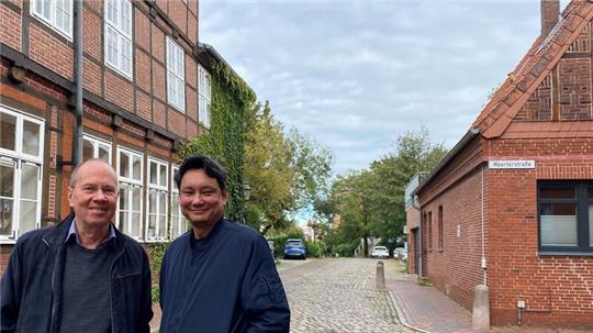 Bernd Utermöhlen und Reiner Sprenger stehen in der Liebfrauenstraße zwischen Stadtbibliothek und Moortorstraße mit dem heutrigen Wehdenhof-Parkplatz im Hintergrund