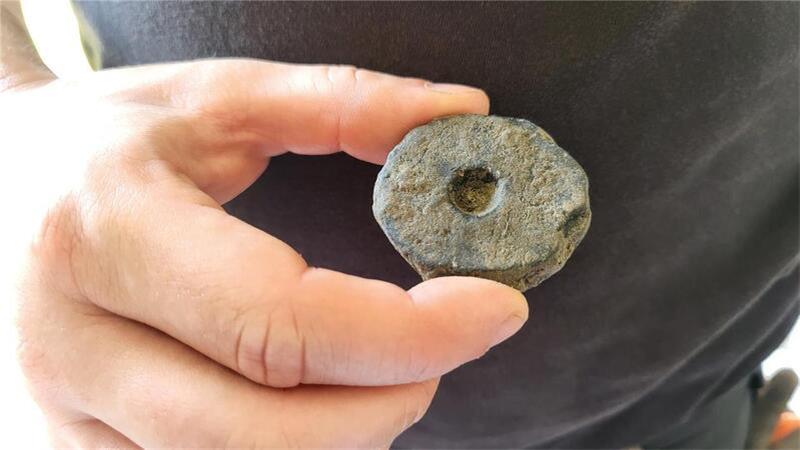 Hier hält der Archäologe eine sogenannte Spinnwirtel in der Hand.