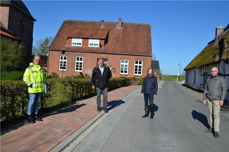 Hier ist der Gehweg bereits saniert. Sigrid Schulz vom Planungsbüro Galla, Bauunternehmer Manfred Licht , Bürgermeisterin Christiane von der Decken und Bauamtsleiter Ernst Hülsen (von links) bei der Baubesprechung in Krummendeich. Foto: Helfferich