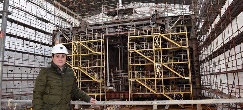 Hinter Pella Sietas-Chefin Natallia Dean ist ein Block des Laderaumsaugbaggers für die Wasserstraßen- und Schifffahrtsverwaltung des Bundes (WSV) zu sehen. Auf der Bauplattform P1 werden die 14 Blöcke verbunden, das 95-Millionen-Euro-Schiff