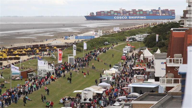 Das erwartet die Besucher beim Duhner Wattrennen 2023 in Cuxhaven Hinter dem Deich ist wieder eine Budenmeile aufgebaut. In Sichtweite der Schiffsverkehr auf der Elbe, hier das 400 Meter lange Containerchiff "Cosco Aries". Foto: Reese-Winne