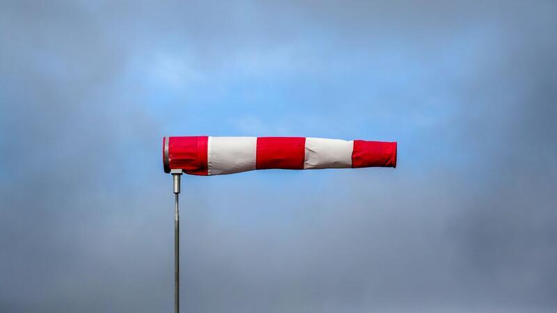 Hinter einem im Sturm stehenden Windsack hat sich eine Wolkenlücke gebildet.