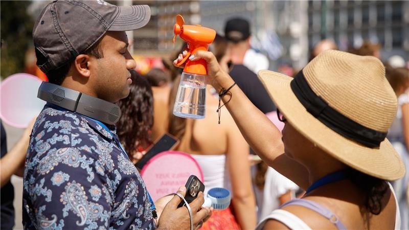 Bilder des Tages Hitze in Griechenland: Touristen versuchen, sich im Zentrum Athens mit einem kleinen Ventilator, der Wassernebel erzeugt, abzukühlen.