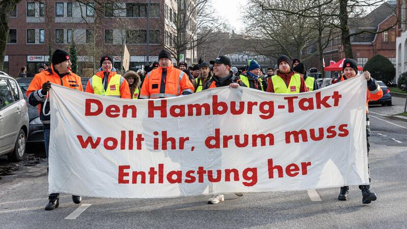 Hochbahnmitarbeiter demonstrieren hinter einem Transparent.