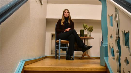 Sarah von Bargen sitzt auf einem Stuhl an einer Treppe im Mehrgenerationenhaus in Horneburg.