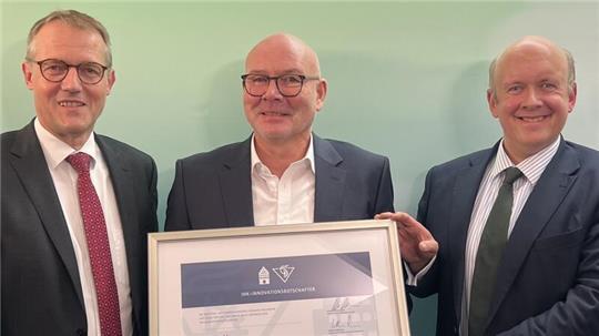 IHK-Präsident Matthias Kohlmann (links) und IHK-Hauptgeschäftsführer Christoph von Speßhardt (rechts) überreichen Björn Strehl (Mitte) die Urkunde.