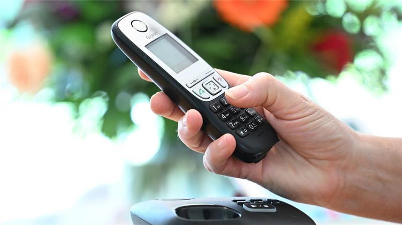 ILLUSTRATION - Eine Frau hölt ein Festnetz-Telefon in ihrer Hand. 