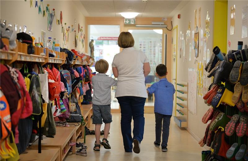 Kinder in Kita gefesselt? Staatsanwaltschaft Stade ermittelt gegen Erzieherinnen Illustraion: Eine Erzieherin geht mit zwei Kindern über den Flur einer Kita (Symbolbild). Foto: Jan-Philipp Strobel/dpa