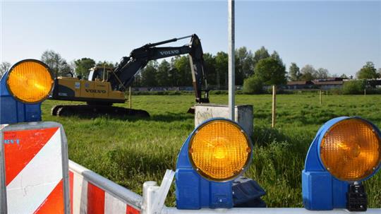 Ein Bagger und Verkehrsbaken an einer Wiese im Gewerbegebiet Felix-Wankel-Straße in Buxtehude.