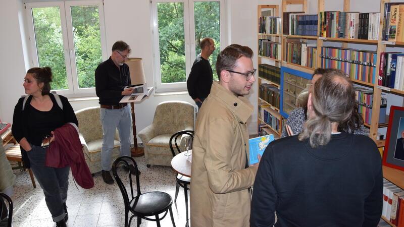 Im Hans-Uwe-Hansen-Raum im Gebäude der Volkshochschule Buxtehude erinnern Bücher und Möbel an den verstorbenen SPD-Politiker und Buchsammler. Zur Eröffnung stöbern Besucher in den Regalen.