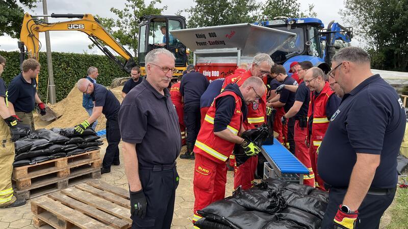 Im Hintergrund ist die Sandsackmaschine zu sehen, sie schafft 4000 Säcke in der Stunde.