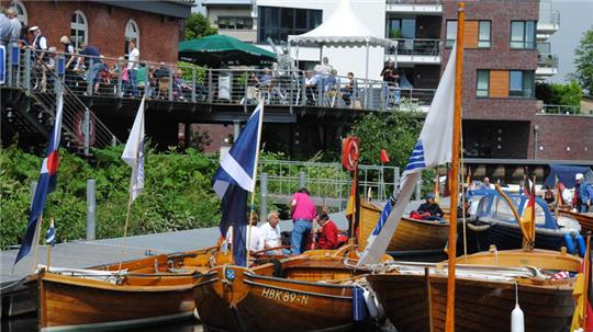 In der Sonne glänzende Tuckerboote am Steg vor dem Buxtehuder Kulturforum am Hafen