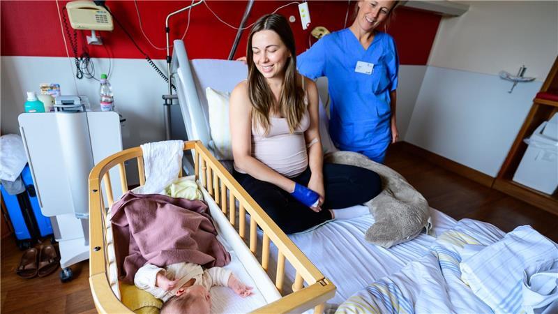 Im Klinikum Lüneburg werden Verena Ahrens und ihre wenige Tage alte Tochter von Hebamme Franziska Pfeil (r) betreut. Frauen können dort seit diesem Monat in Begleitung von zwei Hebammen entbinden.