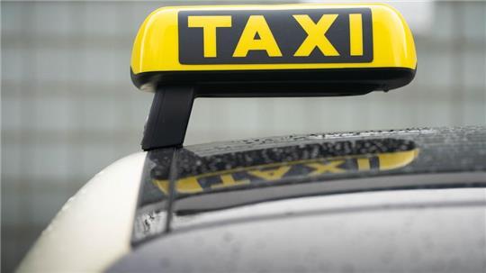 Ein Taxi-Schild ist auf dem Dach eines Fahrzeuges befestigt. 