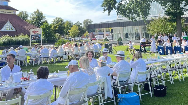 Weiß gekleidete Leute sitzen im Park beim Stadeum.