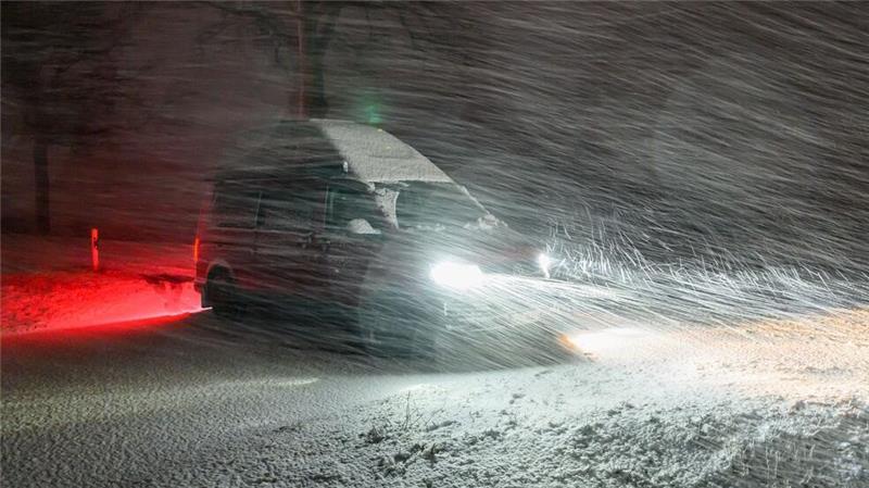 Im dichten Schneetreiben steht am Abend ein Kleintransporter am Straßenrand einer Allee im östlichen Brandenburg.